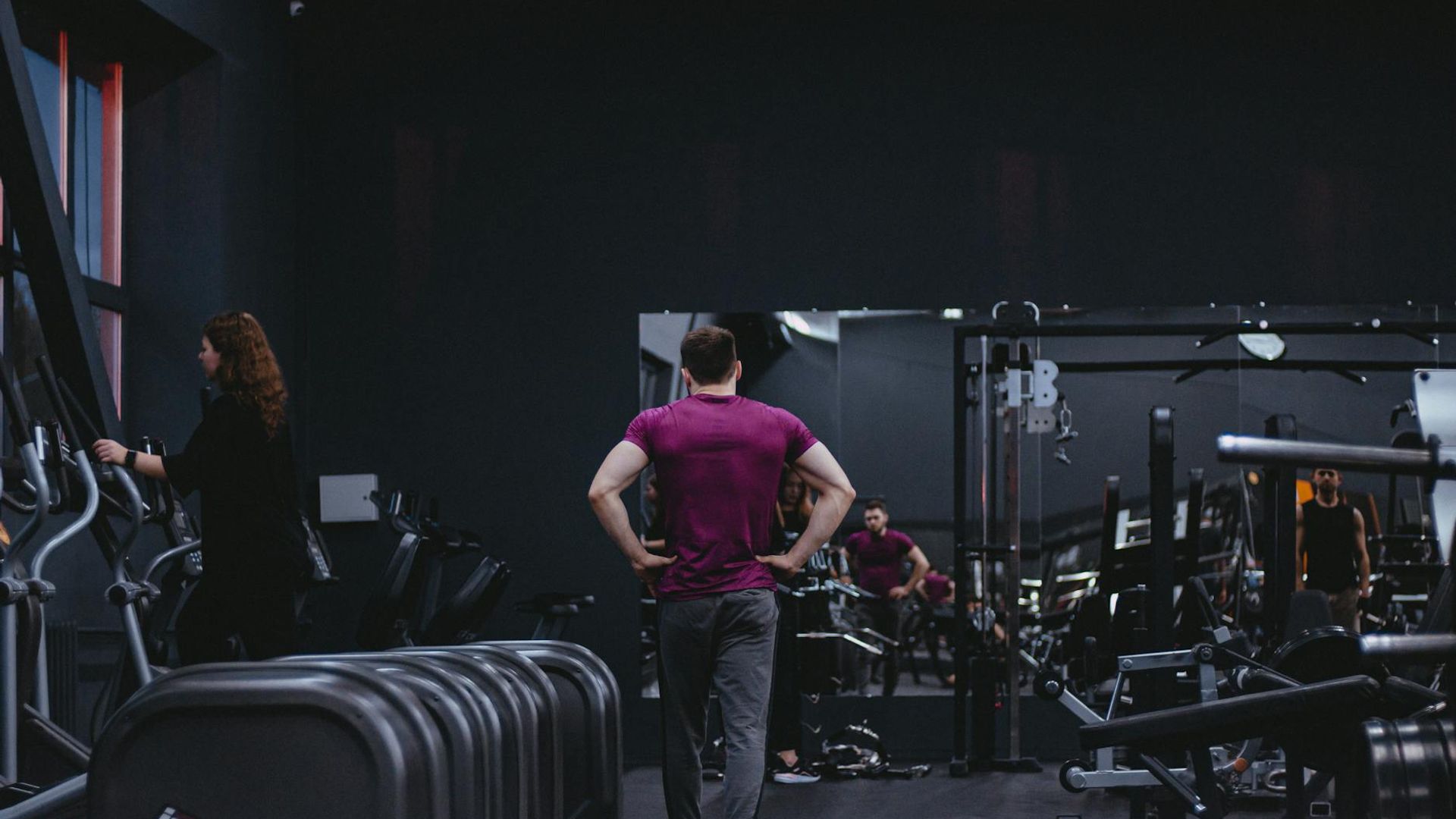 Active man in training gear moving rhythmically in a dark gym